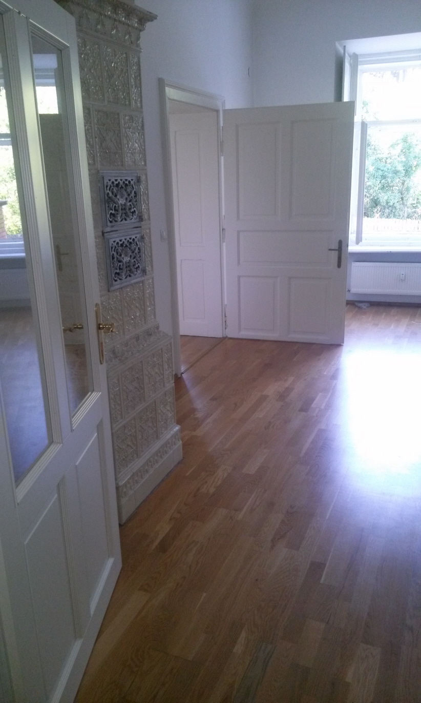 Blick aus der Küche ins Wohnzimmer auf Kachelofen und Schlafzimmertüre